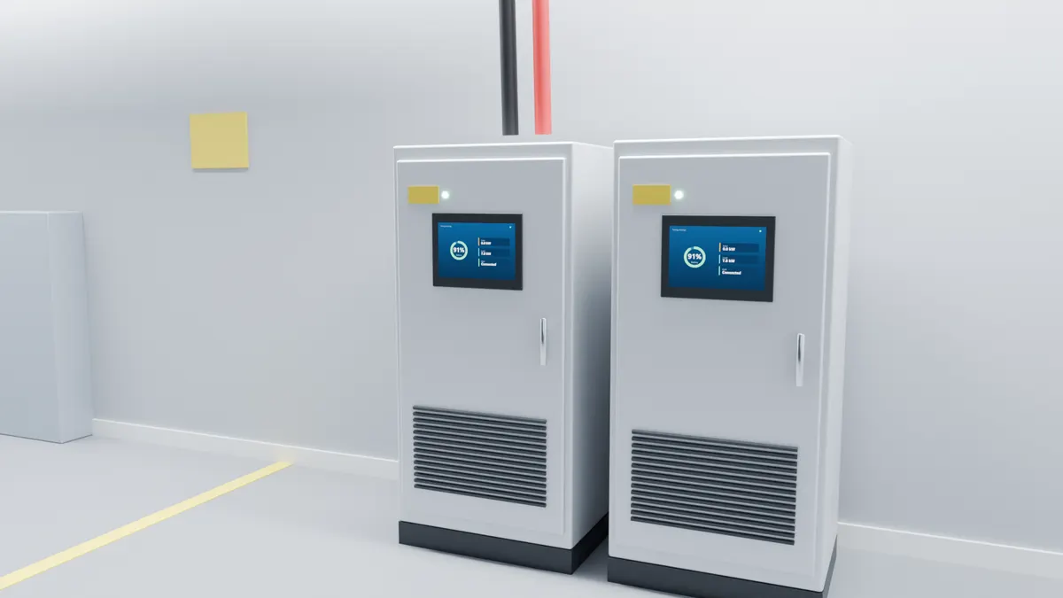 Two floor-standing industrial battery cabinets in a plant room with a cable tray overhead