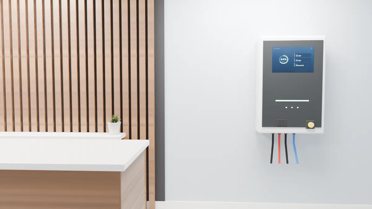 A wall-mounted battery storage unit in a shop or office beside a walnut feature wall and reception counter